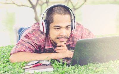 man in grass with headset and computer with study accessories