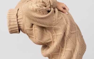 Woman pulling a sweater over her head.